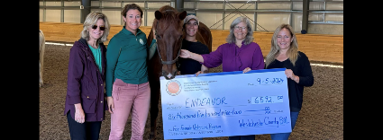 Image of Legislator Erika Pierce presenting a check to individuals at Endeavor Therapeutic Horsemanship