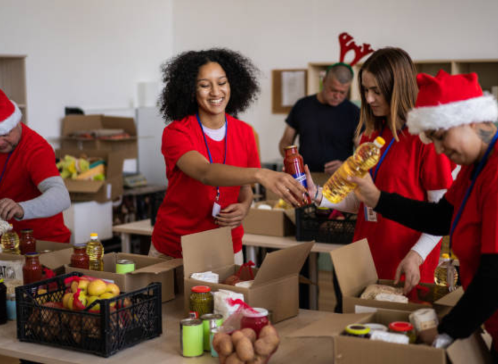 Volunteers in festive attire pack food items into boxes for a holiday donation drive, spreading joy and helping the community.